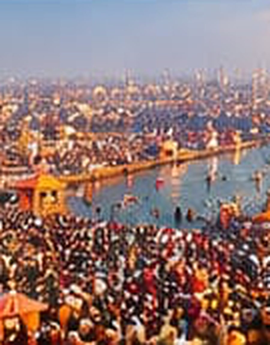 Aerial view of a vast gathering of devotees at the river during a sacred bathing festival